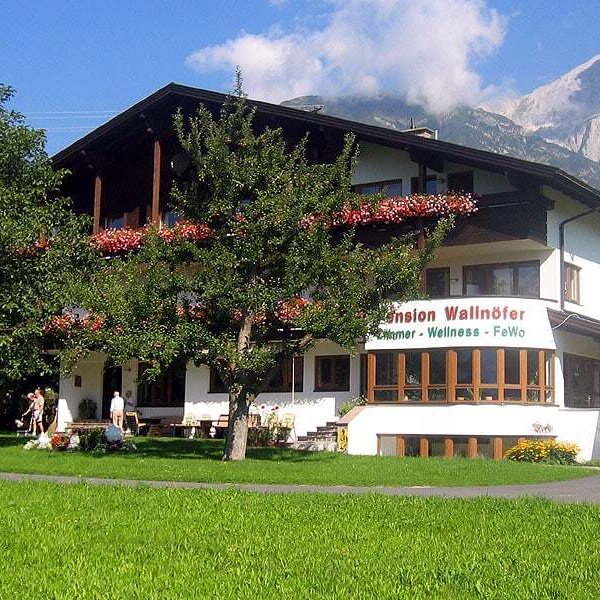 The Farm House, featuring balconies with flower boxes and a surrounding green lawn, offers views of the mountains.