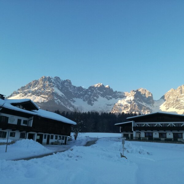 The Farm House in a winter setting, with snow-covered grounds and prominent mountains in the background.