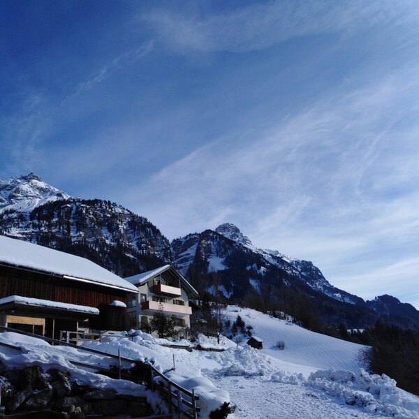 Außenansicht des Bauernhofs in der verschneiten Berglandschaft.