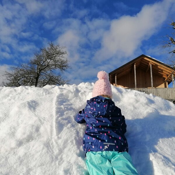 Kind beim Winterspiel im Schnee auf dem Bauernhof.